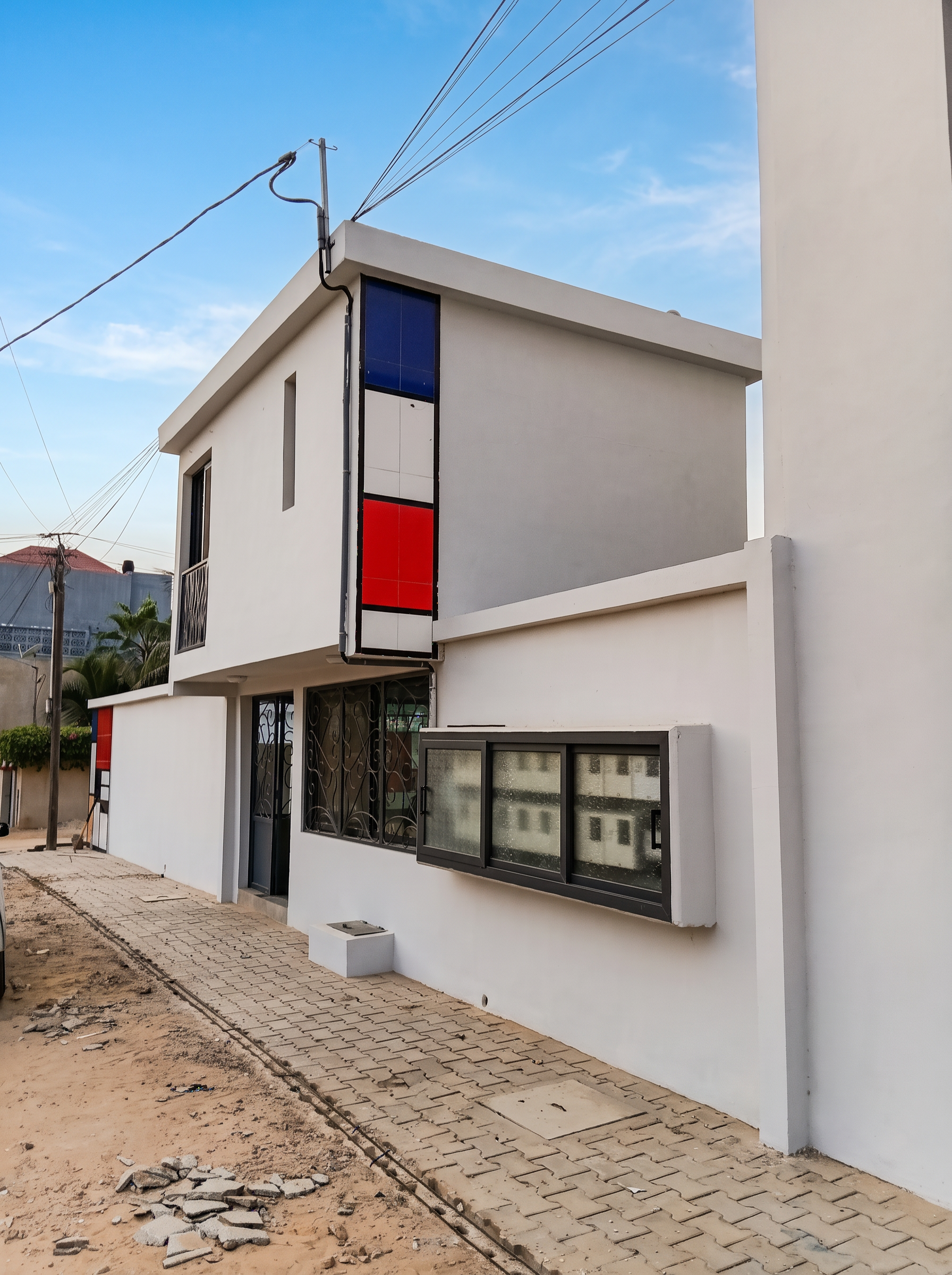 Façade extérieure blanche de la résidence Le Mondrian à Saly Portudal ornée d'un bandeau vertical bleu, blanc et rouge